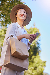 Image showing Phone, asian woman and shopping bag with happy, smile and technology with 5g web outdoor. Happy young person texting, internet networking and doing a social media app scroll online with happiness