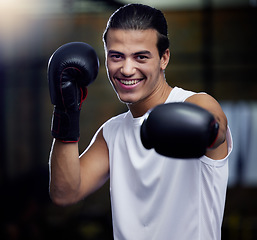 Image showing Portrait, fitness and boxing man punching with boxing gloves in a sport gym for health. Athlete, boxer and face of strong male personal trainer prepare for a fight or kickboxing and muay thai event