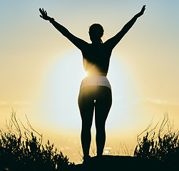 Image showing Motivation, nature and silhouette of woman at sunrise enjoying morning, peace and freedom by ocean. Inspiration, calm and back of girl with arms raised for spiritual worship, wellness and meditation
