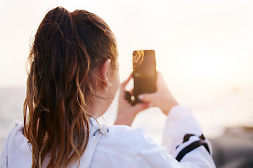 Image showing Woman, back or phone picture of beach sunset by ocean or sea in nature environment, holiday vacation or Canada travel location. Student, tourist or influencer on mobile photography technology or vlog