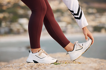 Image showing Stretching, legs and woman on a beach rock, start fitness and yoga exercise in nature of Portugal. Warm up, training and feet of an athlete at the ocean for spiritual health, cardio or pilates