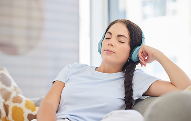 Image showing Headphones, relax and young woman on a sofa listening to calm music, radio or podcast in her living room. Peace, zen and comfortable lady streaming audio, playlist or album on a couch at her home.