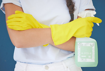 Image showing Cleaning woman and arms crossed with spray product for home hygiene and sanitation routine in blue studio. Housekeeping girl with detergent chemical bottle and safety gloves for spring cleaning.