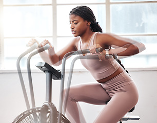 Image showing Motion blur, exercise bike and black woman in gym for workout, cardio training and moving with speed, energy and motivation. Fitness girl, stationary cycling machine and air bike, wellness and action