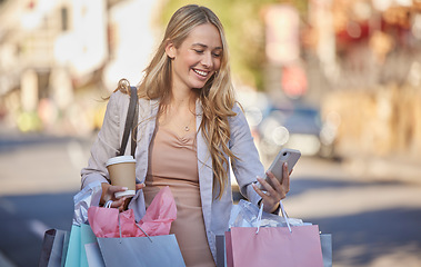 Image showing Shopping bag, smartphone and woman in city street with coffee for gift planning, holiday discount and fintech deal on e commerce app. Shopping, retail and customer using phone, walking in urban road