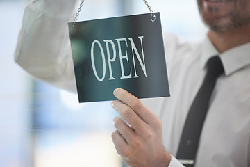 Image showing Businessman, advertising open sign and window in office of new business, company or startup agency. Closeup of executive hanging signage for opening day at glass display, announcement and information