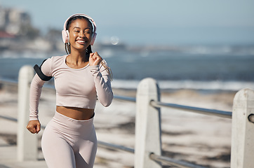 Image showing Beach, fitness and headphones woman running with audio technology for fitness, exercise and speed inspiration in urban city. Black woman, athlete or runner listening to music with fast workout at sea