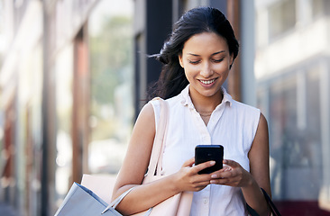 Image showing Woman, smartphone and shopping bag in city, connect and purchase expensive product. Young Hispanic female, girl and consumer typing on phone, boutique item and customer with clothes, sale or discount