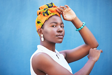 Image showing Black woman, beauty and turban for face of african culture, fashion and freedom on a blue background wall for cosmetics, head scarf and makeup mockup. Portrait of female from Nigeria posing for art