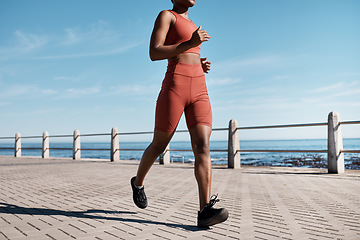 Image showing Black woman, legs or running by city beach, ocean or sea in healthcare workout, cardiovascular wellness training or marathon exercise. Runner, sports athlete or personal trainer on promenade fitness