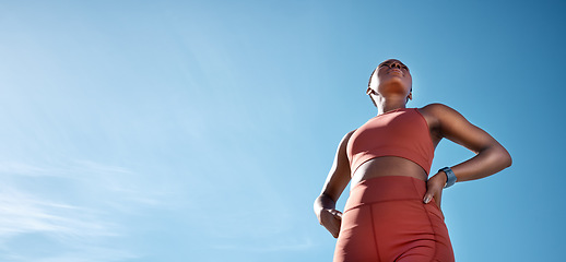 Image showing Fitness, black woman and blue sky, mockup and background of vision, mindset and motivation for exercise goals, healthy lifestyle or body wellness. Low angle, female sports athlete and outdoor mock up