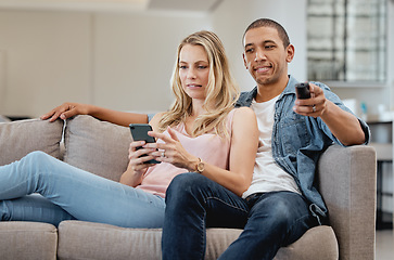 Image showing Curious, jealous and couple watching tv with a phone, social media and movie on living room sofa. Relax, jealousy and man reading communication on mobile app of a woman while on the couch for a film