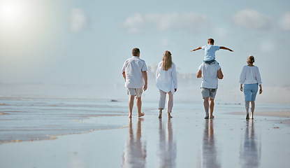 Image showing Family, beach and men with women and child from back with blue sky on outdoor summer vacation. Happy family mother, father and kid with piggy back fun walking in sun and quality time together at sea.