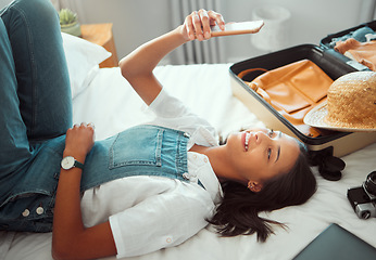 Image showing Selfie, vacation and relax with a woman lying on a hotel bed with luggage after unpacking on vacation. Social media, phone and bedroom with a young female enjoying travel or hospitality as a tourist