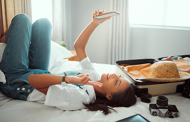 Image showing Peace, phone or girl taking selfie on a bed for social media with luggage in airbnb, apartment or hotel room. Relax, freedom or happy traveler smiles taking pictures with hand gesture or sign alone