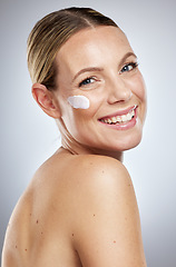 Image showing Portrait, face or woman with cream for skincare, self care or healthy glowing skin with studio background. Wellness, dermatology or happy beauty model smiles with facial lotion or sunscreen in Berlin