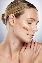 Image showing Makeup shade, cosmetics and face of a woman with foundation, facial cream and skincare on a grey studio background. Lotion, bb cream and cosmetic model with swatches of concealer to check for a match