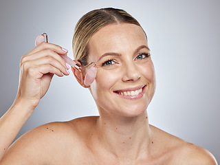 Image showing Woman, face and smile with makeup roller for skincare, hygiene or cosmetics against a grey studio background. Portrait of happy female smiling in satisfaction with rolling tool for cosmetic facial