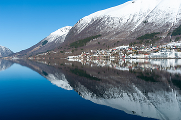 Image showing small town under high mountains reflected in the blue sea