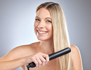 Image showing Hair care, salon styling and woman with straightener, marketing product and happy with ceramic ironing on grey studio background. Luxury, beauty salon and face portrait of a model straightening hair