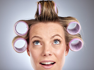 Image showing Hair, rollers and beauty with a model woman in studio on a gray background for a hairstyle using curlers. Hair care, thinking and face with an attractive young female styling her curly extensions