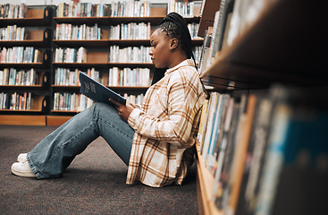 Image showing Library, college student and black woman reading books on ground floor for education, studying and campus learning. University student, girl and bookshelf for project, knowledge and academy research