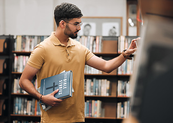 Image showing Bible, university or student in a library to research spiritual religion knowledge, prayer or Christianity by bookshelf. Nerd, school, focused young man in college studying or learning faith in God