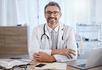 Image showing Healthcare, hospital and portrait of doctor at desk for trust, medical support and ready for consultation. Wellness, medicine and senior health care worker with laptop, book and insurance paperwork