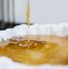 Image showing Honey production, extraction and drip in factory with sweet gold, splash and filter cloth in container. Honeycomb harvest, manufacturing and process with machine, liquid and beekeeping in California