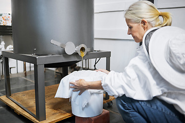 Image showing Beekeeper woman, honey production and machine in factory, workshop and organic harvesting process. Apiculture expert, natural product and working with ppe bee suit for manufacturing healthy food