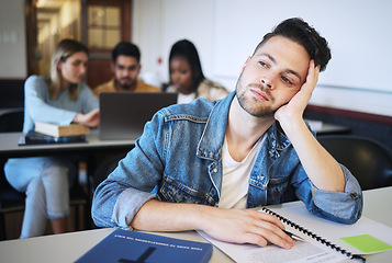 Image showing Education, university and bored student in classroom thinking studying for exam. Sad young man at college, boredom and stress, depression or anxiety with book and academic students at desk on campus.