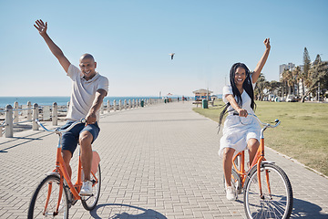 Image showing Couple, bicycle and celebrate happiness for freedom on beach, travel holiday and summer vacation. Happy man, woman smile and cycling bike, cheerful and laughing together for love in ocean sidewalk