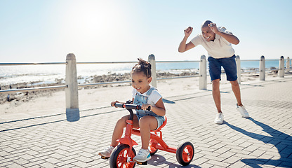 Image showing Ocean, bicycle and happy father with girl excited after learning, teaching and helping kid ride bike. Black family, love and dad celebrate with child on summer holiday, vacation and weekend by sea