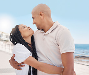 Image showing Love, hug and happy couple at beach promenade for summer vacation, holiday and freedom in sunshine. Man, woman and people hugging outdoor at ocean sidewalk for travel, peace and happiness together