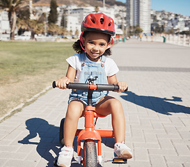 Image showing Portrait, girl child and cycling on sidewalk, learning to ride bike or healthy childhood development. Happy kid riding tricycle with helmet, safety and outdoor fun in summer, sunshine and Atlanta USA