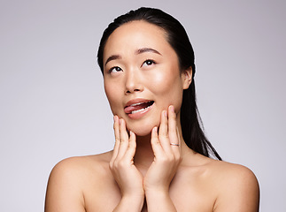 Image showing Asian woman, hands and face in beauty skincare for facial cosmetics or treatment against a studio background. Japanese woman smiling with tongue out in satisfaction for hygiene or perfect skin
