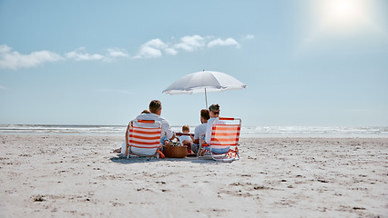 Image showing Family, relax and picnic in the sun on the beach for summer vacation, holiday or weekend getaway in the outdoors. People relaxing by the ocean coast with chairs and umbrella for free time in nature