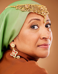 Image showing Mature muslim woman, face or fashion hijab on studio background with traditional jewellery, religion jewelry or trendy accessory. Zoom, portrait or middle aged Islamic model in stylish hijab earrings