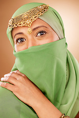 Image showing Fashion, tradition and face of a muslim woman in studio with traditional jewelry and burka. Beauty, islam and portrait of mature lady with islamic hijab scarf or arabic jewellery by brown background.