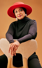 Image showing Fashion, beauty and muslim woman on chair with stylish hat, cosmetics and trendy makeup on studio background. Mature model portrait, islamic hijab and culture, lifestyle or luxury clothes in Malaysia