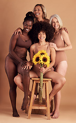 Image showing Plus size women, lingerie and group portrait with sunflower for beauty, wellness and solidarity in studio. Model team, underwear and flowers with support hug, diversity and smile by studio backdrop