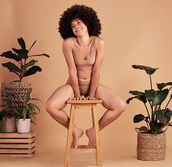 Image showing African woman, lingerie and studio with smile, stool and plants for natural material underwear. Black woman, happy and sustainable cotton fabric with leaves, self love and beauty by beige background