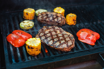 Image showing Beef steaks on the grill with flames