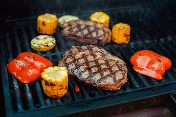 Image showing Beef steaks on the grill with flames