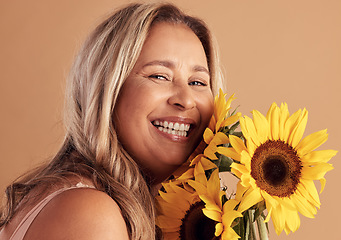 Image showing Mature woman and beauty portrait with flower bouquet and happy smile for natural skincare campaign. Wellness, cosmetics and healthy skin of latino person with sunflowers on beige studio background.