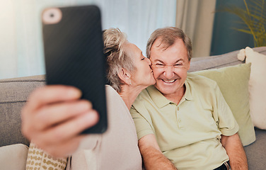Image showing Senior, kiss and phone selfie of a couple with love, care and happiness on a living room sofa. Happy, smile and marriage of a wife and man together on wifi with mobile phone photo for social media