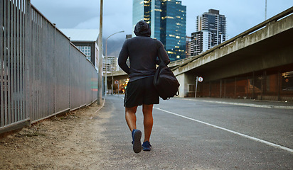Image showing Fitness, black man and walking on city street after running, exercise and gym workout with a hoodie at night. Back of a male athlete in urban Miami for a walk and cardio training with a duffle bag