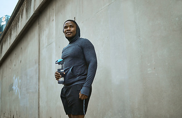 Image showing Fitness, water bottle and black man in city after training, exercise and running. Sports, break and male runner with refreshing liquid after jog, exercising or workout in town or street in winter.
