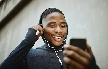 Image showing Music, phone and running with black man in city for streaming, podcast and mobile radio. Workout, health and cardio with face of runner with earphones by wall for training, sports and endurance