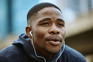 Image showing Face, music earphones and black man in city streaming radio or podcast on break after exercise. Sports, fitness and male from Nigeria listening to workout song while thinking of running in winter.